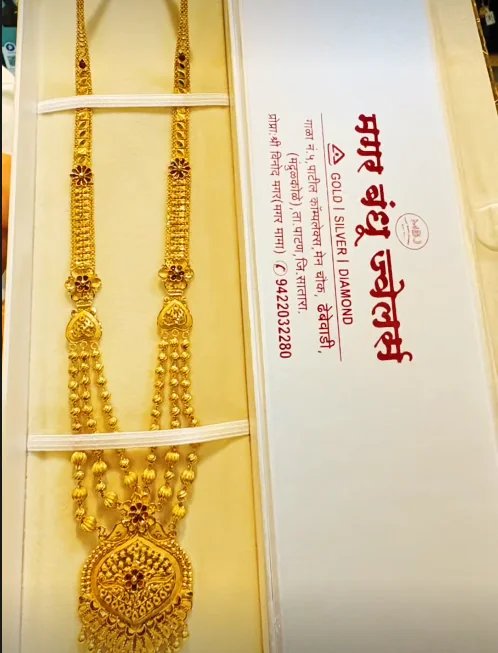 Long gold haar necklace with layered bead strands and an ornate pendant, presented in a Magar Bandhu Jewellers box